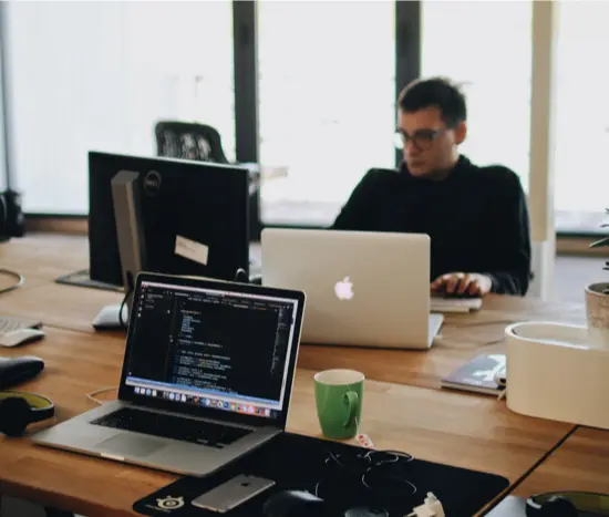 Colleagues working at laptops in a bright open-plan office.